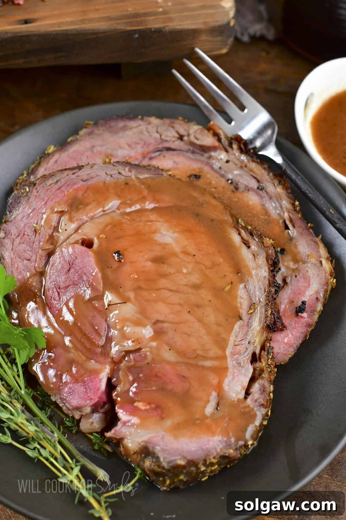 closeup of two slices of prime rib topped with au jus.