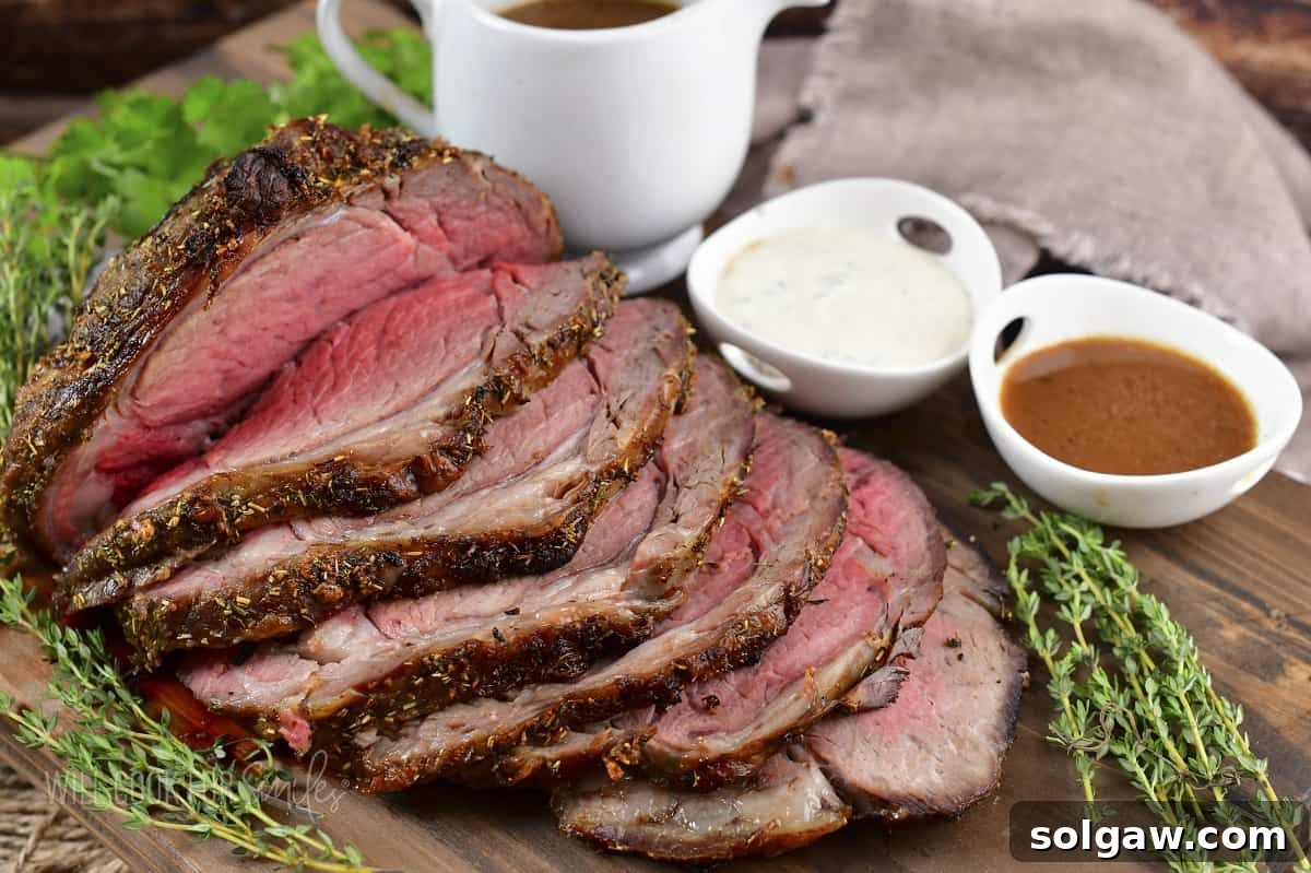 sliced prime rib on a wooden board with au jus and horsey sauce in bowls.
