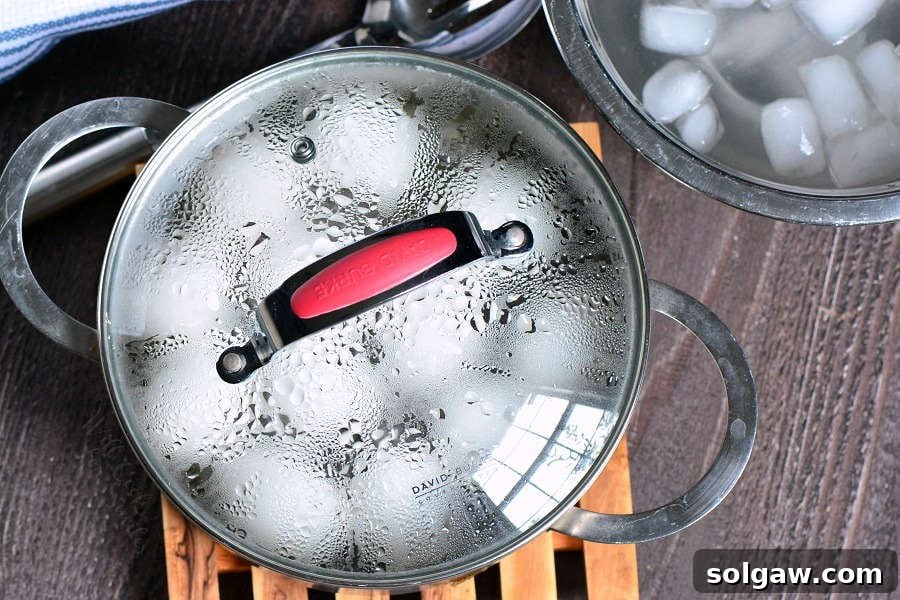 Hard boiled eggs in a metal pot with a lid, sitting off the heat to finish cooking evenly.