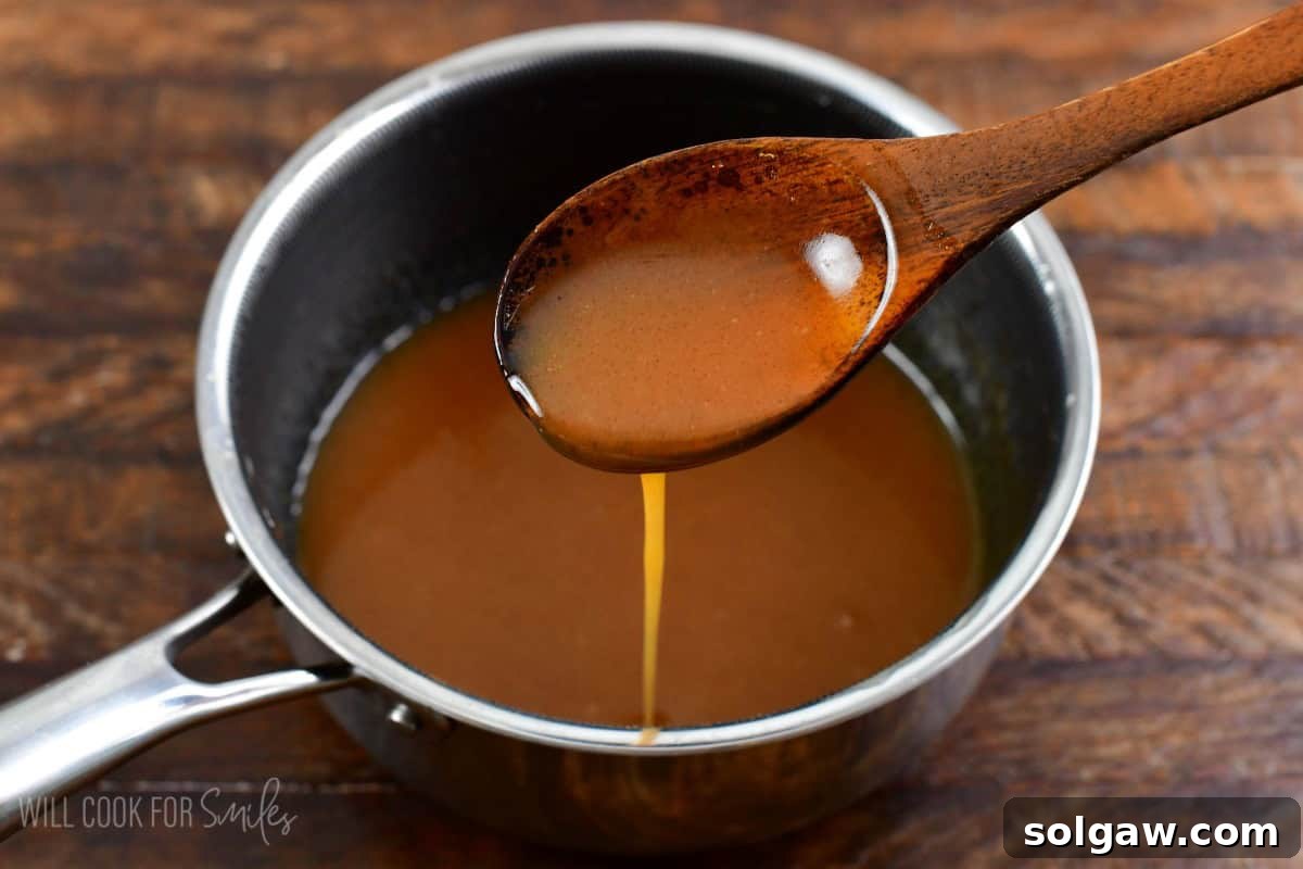 A hand scooping sweet buttery syrup from a small bowl, ready to drizzle over French toast.