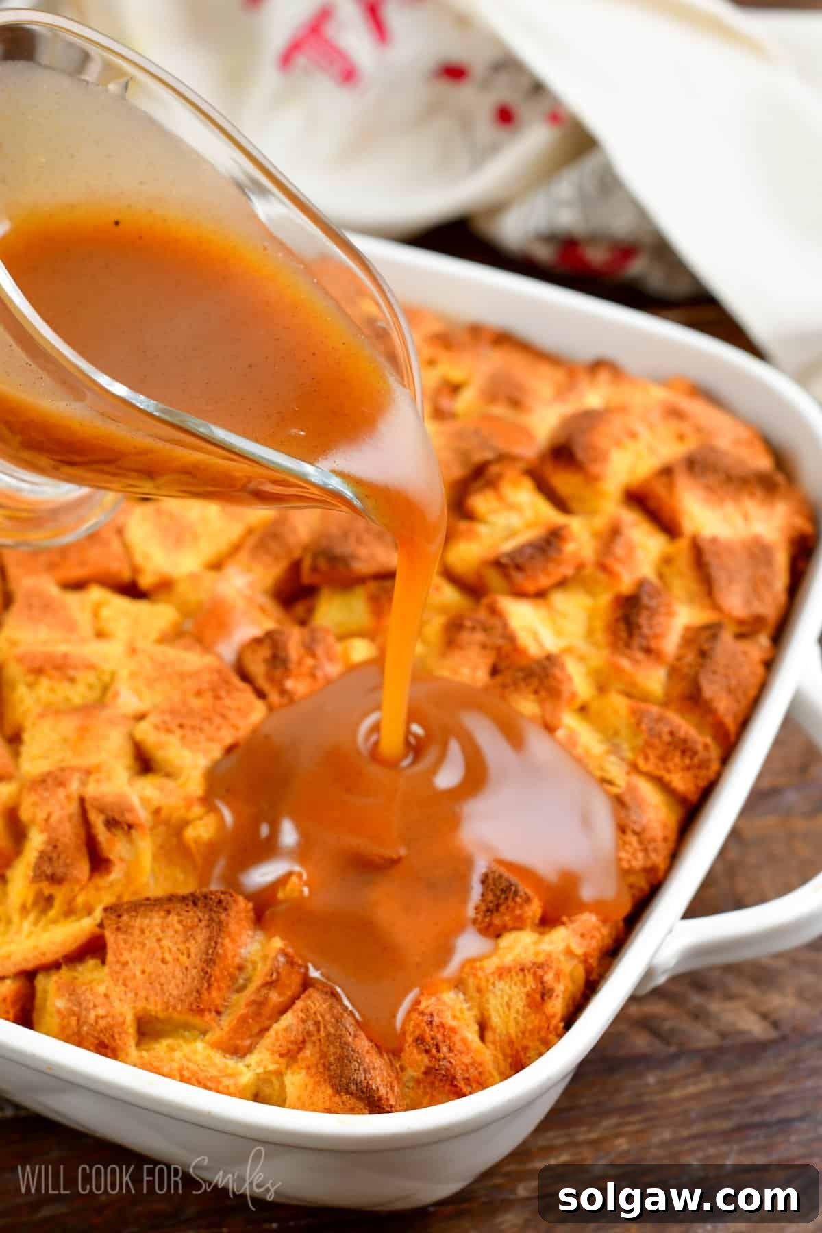 Generously pouring rich, sweet syrup over a freshly baked French toast casserole, creating a luscious glaze.