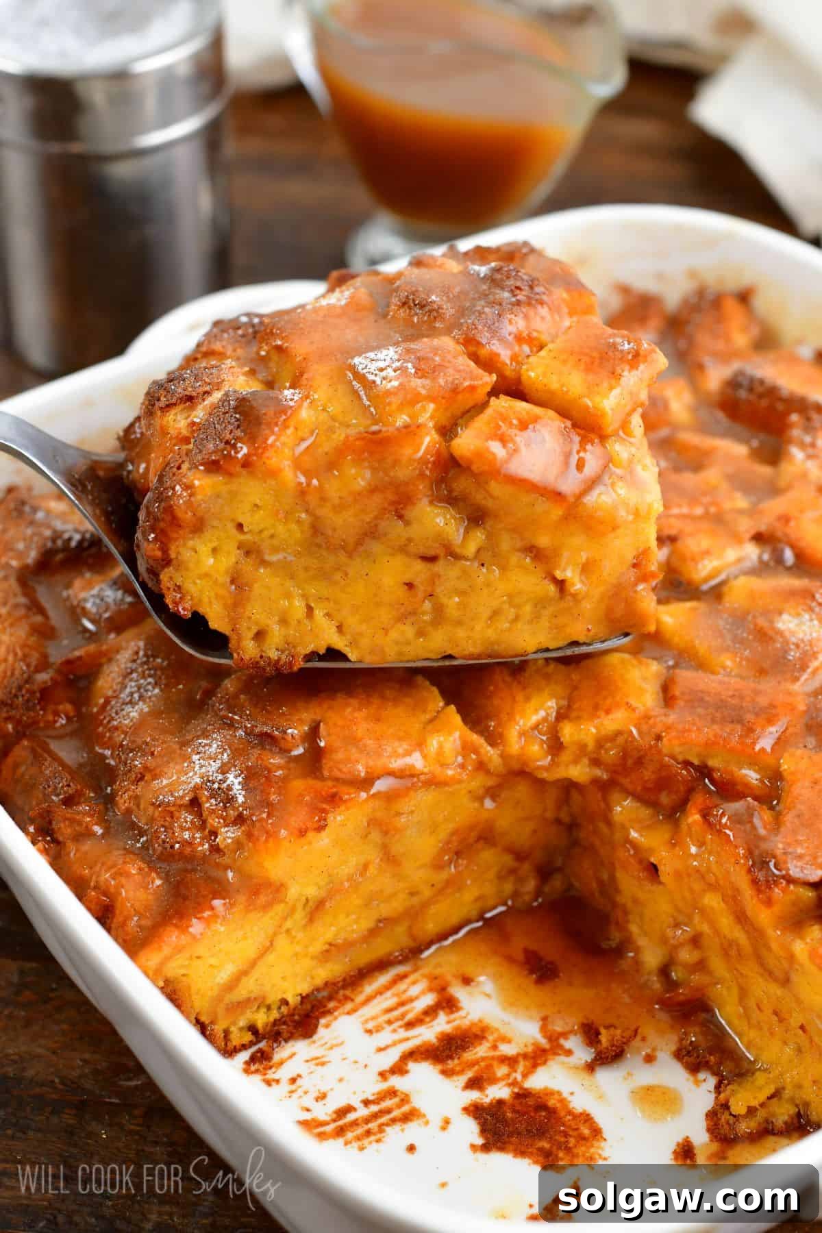 A delicious slice of French toast casserole, golden and fluffy, resting on top of the full casserole in its baking dish.