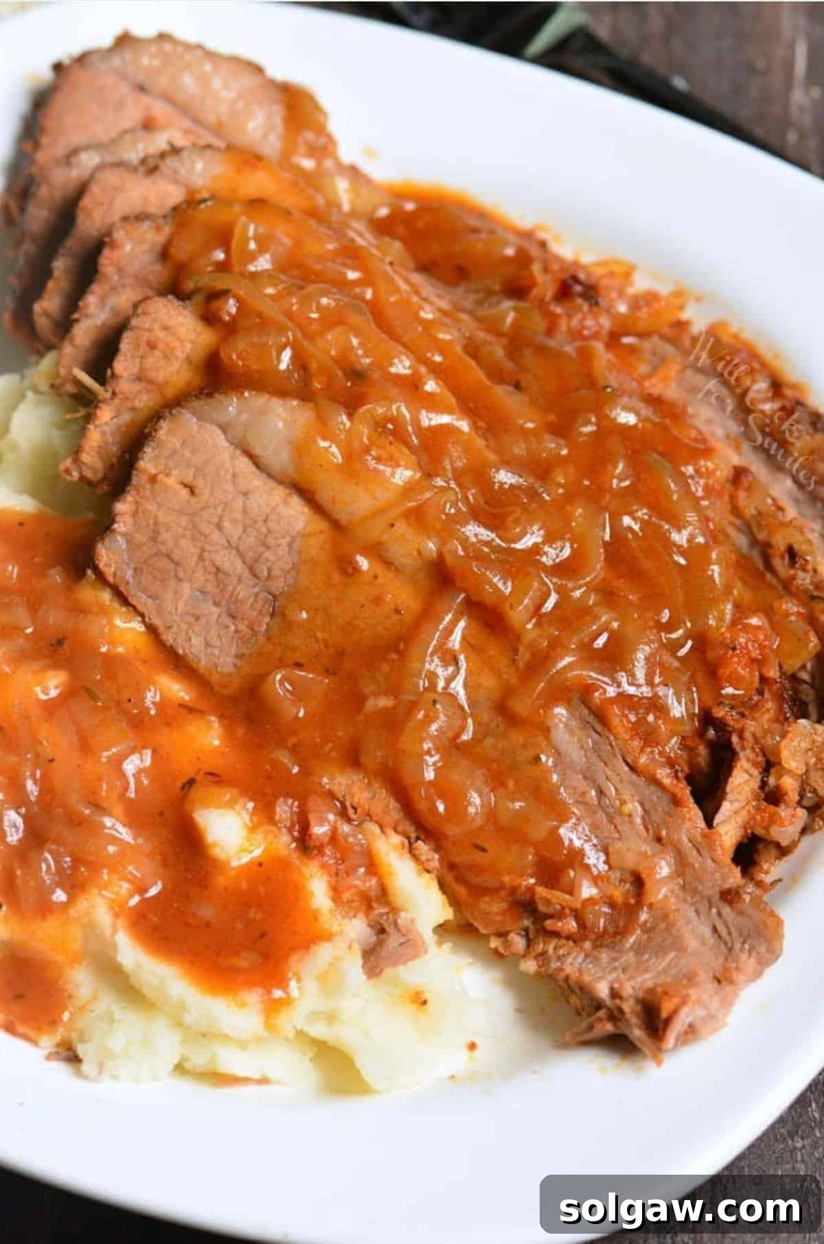 French onion brisket sliced and covered in sauce over fluffy mashed potatoes. 