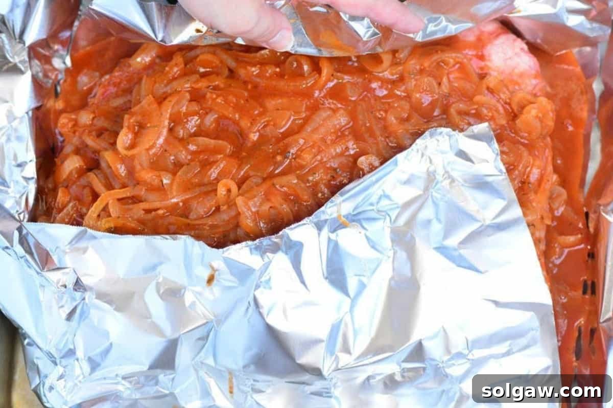 covering the uncooked beef brisket in French onion sauce with foil in roasting pan.