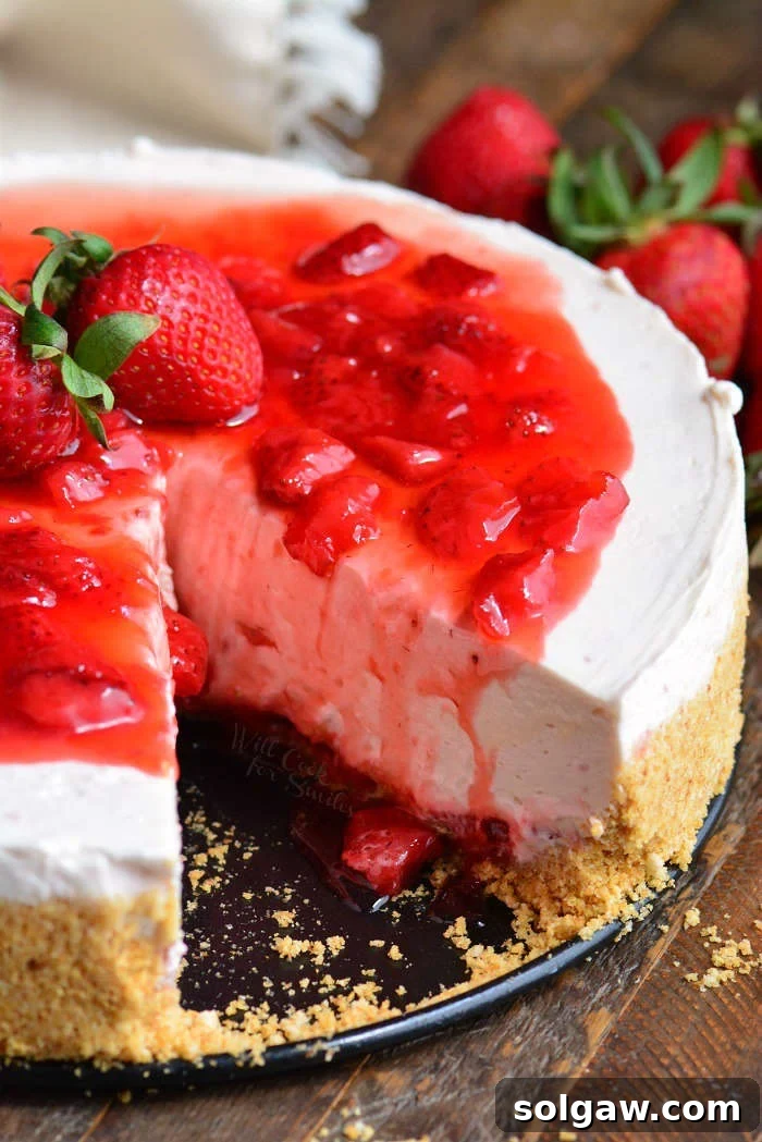 Homemade Strawberry No-Bake Cheesecake with a slice removed, showing the layers.
