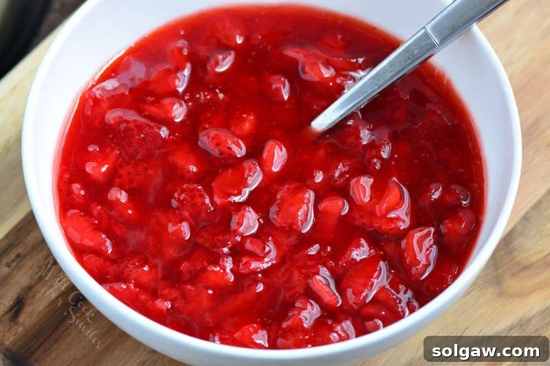 Homemade strawberry filling simmering in a white pot