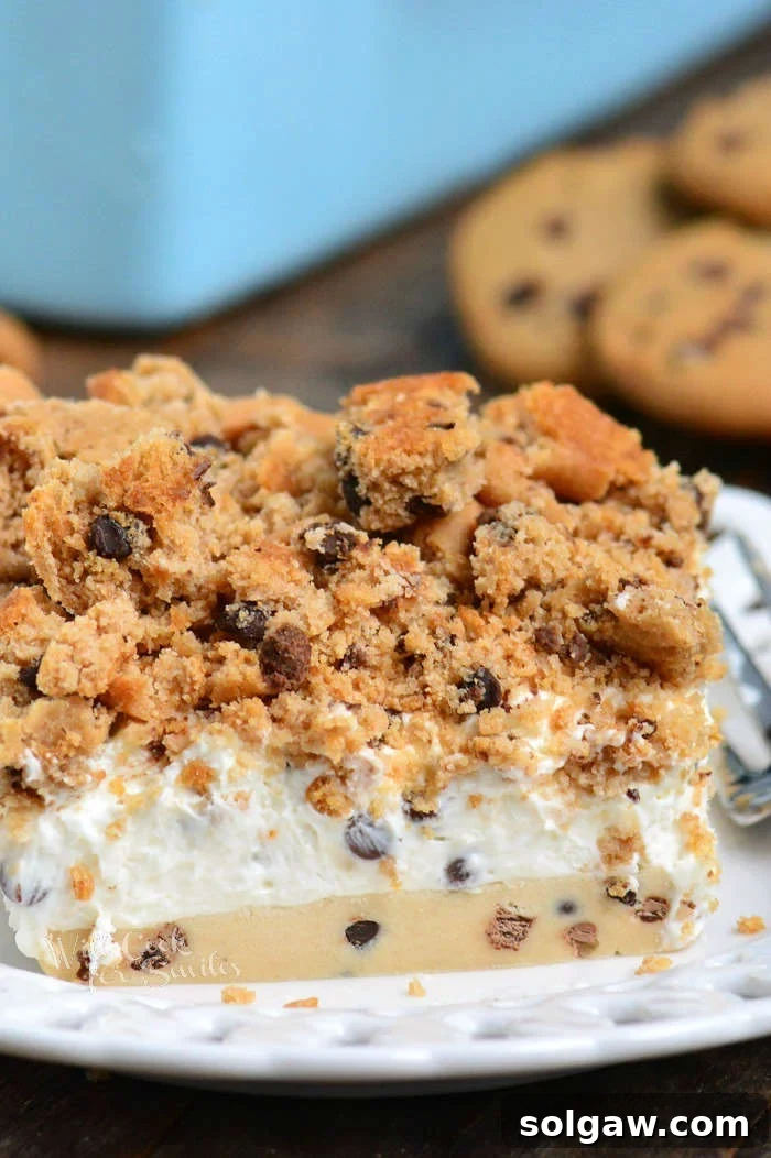 A perfectly sliced piece of Cookie Dough No Bake Cheesecake on a white plate, showcasing its distinct layers.