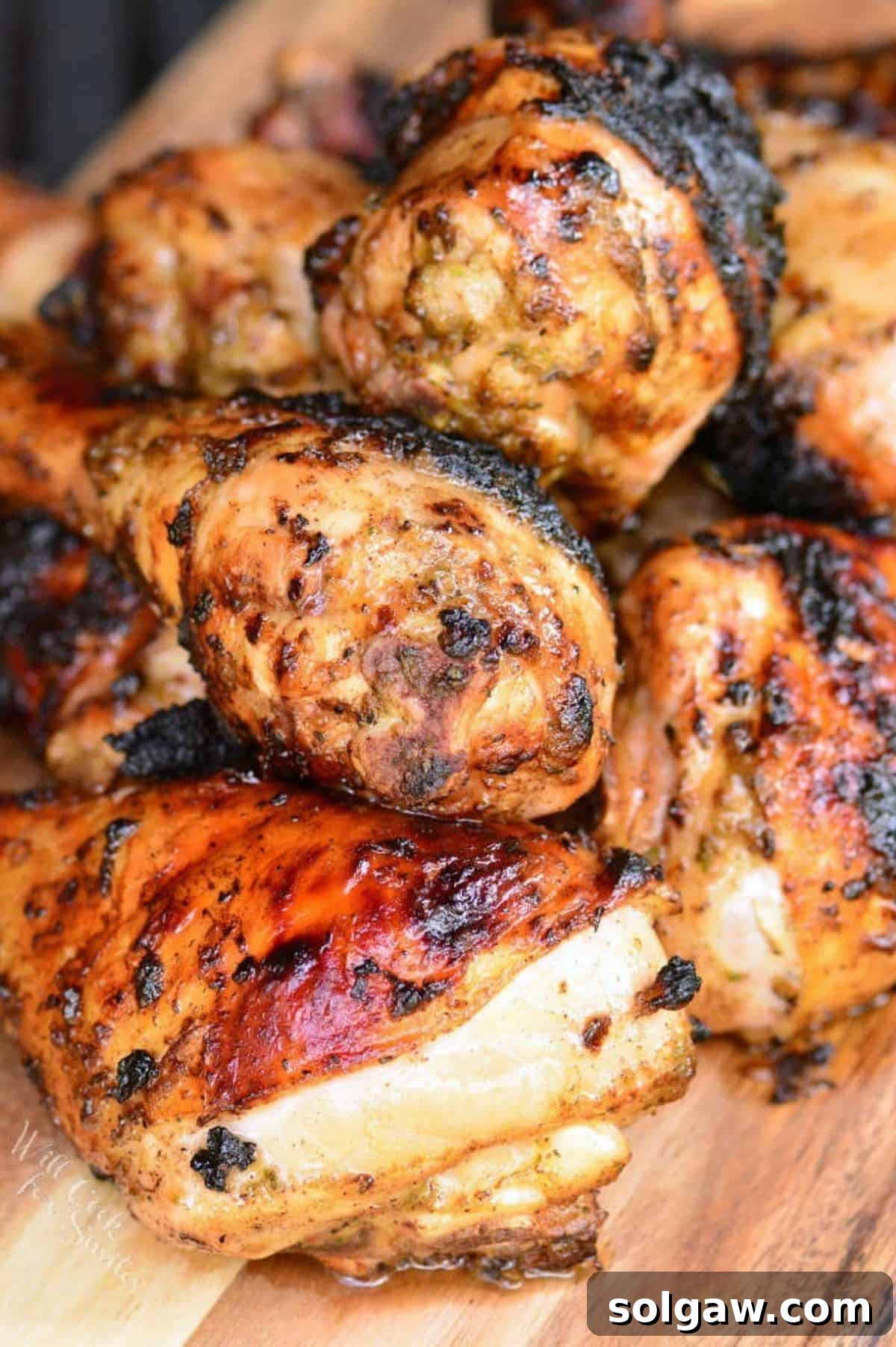 cooked jerk chicken drumstick stacked on the wooden plate.