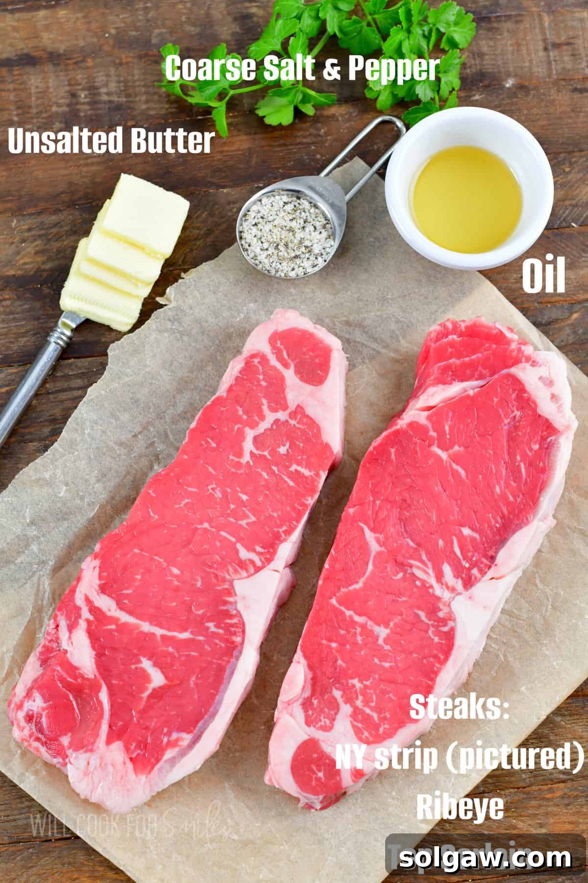 A collection of essential ingredients for cooking steaks, including raw steaks, coarse salt, freshly ground black pepper, and a pat of butter, arranged on a rustic wooden surface.