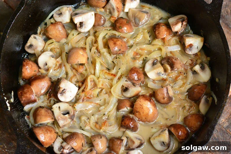 Savory mushrooms and onions caramelizing in a skillet, bathed in a rich broth and aromatic seasonings.