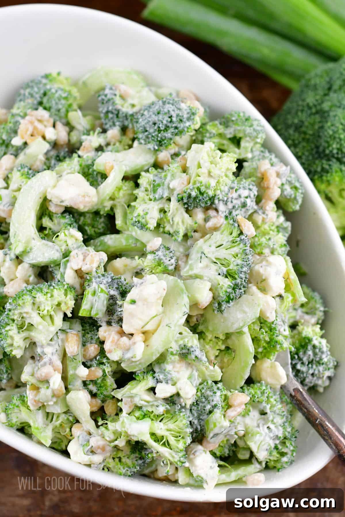 green broccoli salad with cucumber nuts and feta in a white bowl.
