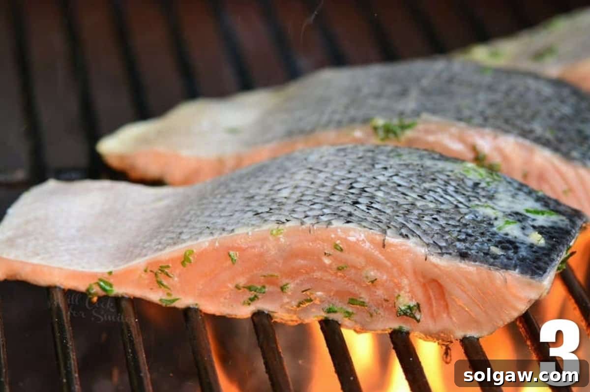 salmon filets cooking on the grill skin side up.