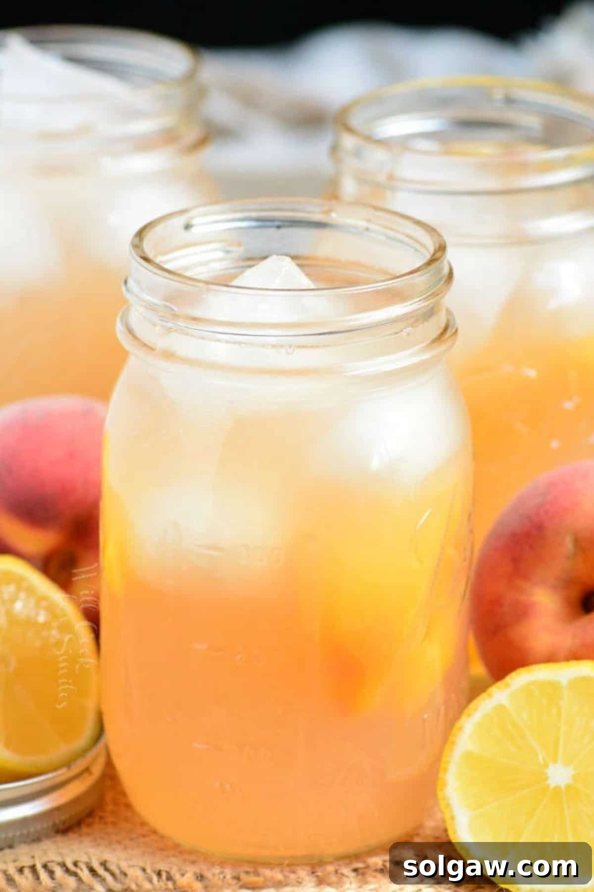 A vibrant glass of homemade peach lemonade with ice, garnished with fresh peach slices, inviting a refreshing sip on a sunny day.