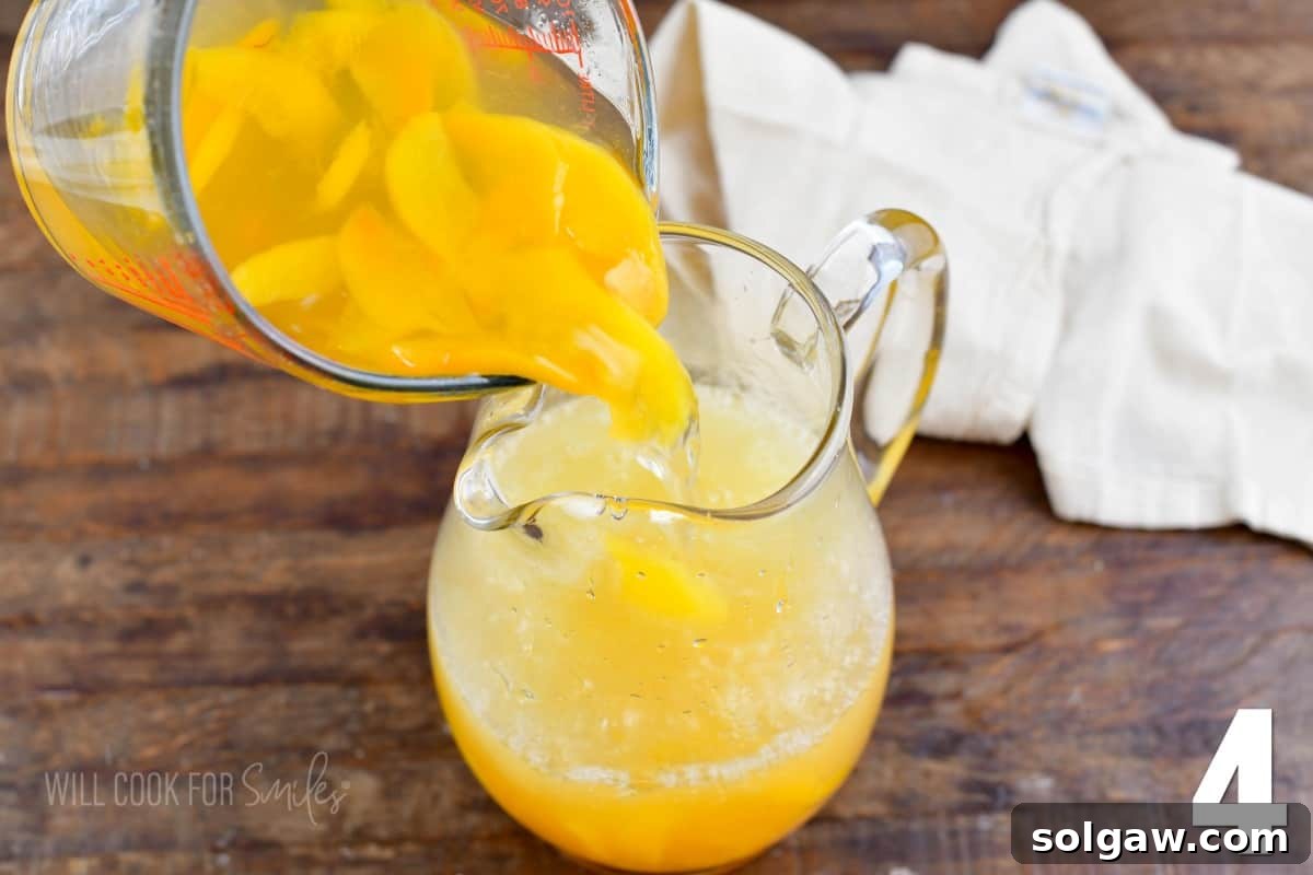 Pouring the luscious peach syrup and lemon juice mixture into a glass pitcher, preparing for a refreshing batch of homemade peach lemonade.