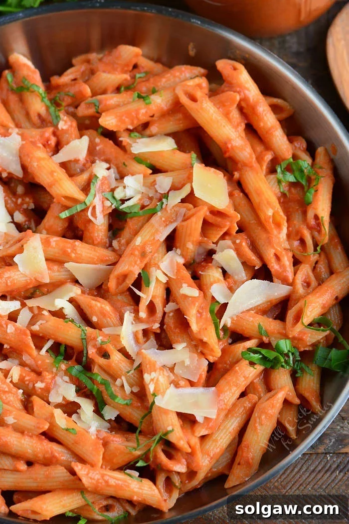 Creamy Vodka Sauce mixed perfectly with penne pasta in a metal bowl, garnished with fresh basil, ready to serve