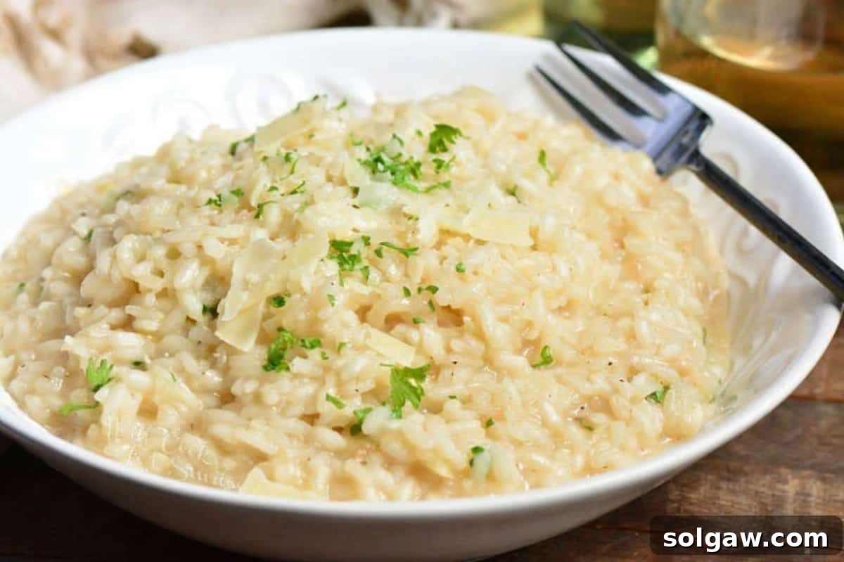 Creamy Grana Rice 7 A bowl of creamy parmesan risotto garnished with fresh parsley and cheese, with a fork beside it.