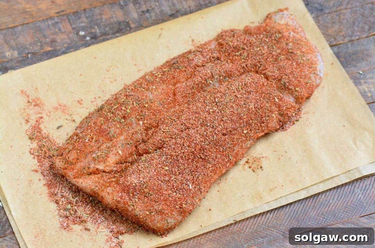 blackened seasoning on a fish filet on a sheet of parchment paper.