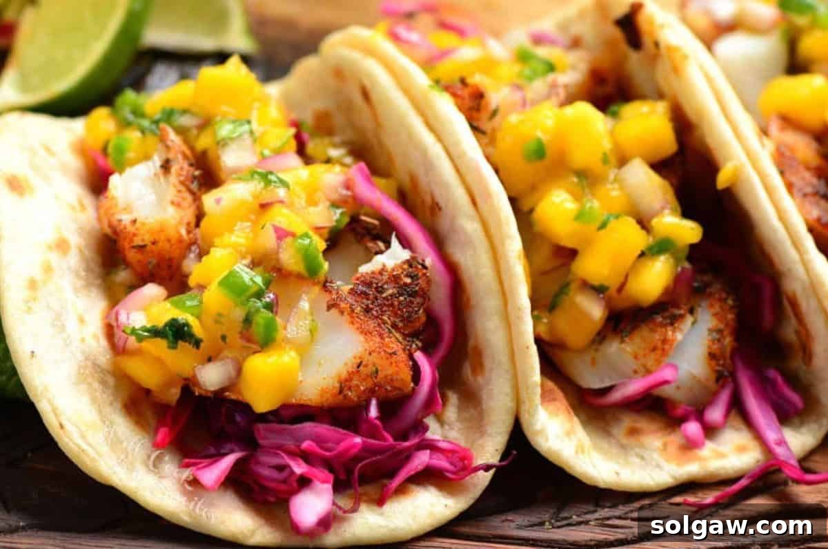two fish tacos with mango salsa on top of them.