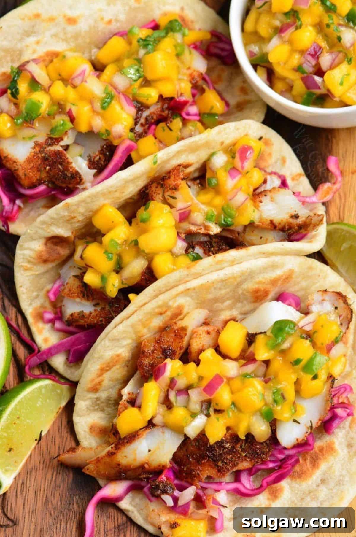 Three blackened fish tacos with mango salsa on top.