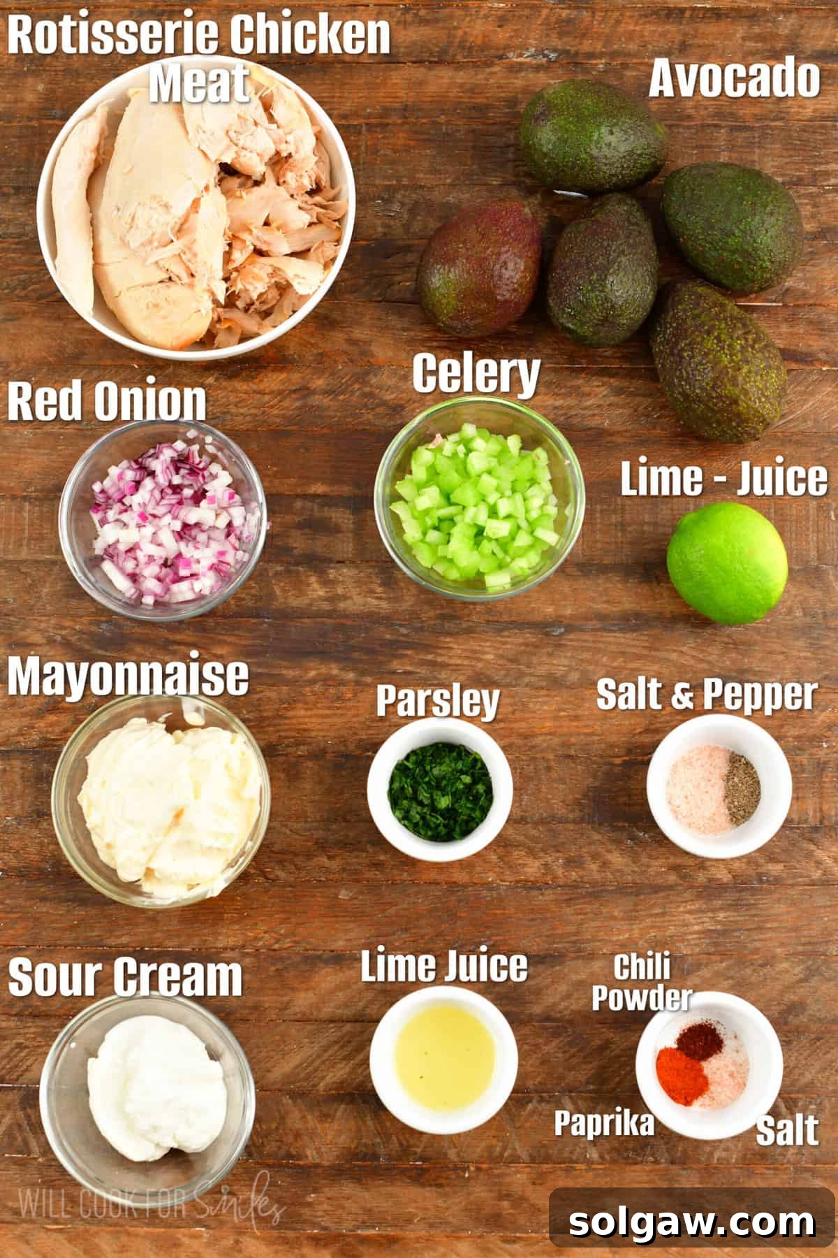 labeled ingredient to make chicken salad stuffed avocadoes on a wooden board.