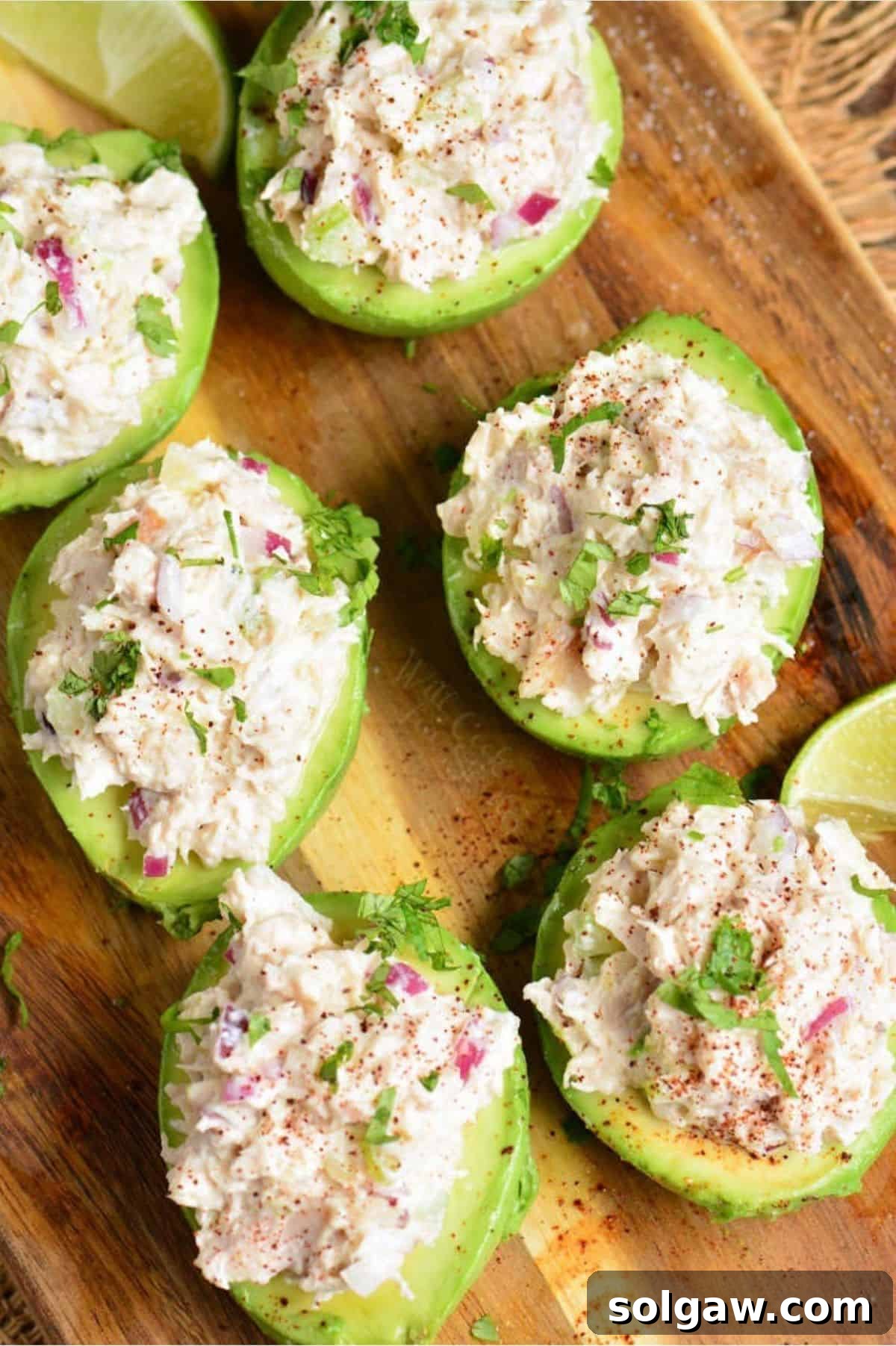 six stuffed avocado halves topped with chicken salad on the wooden board.