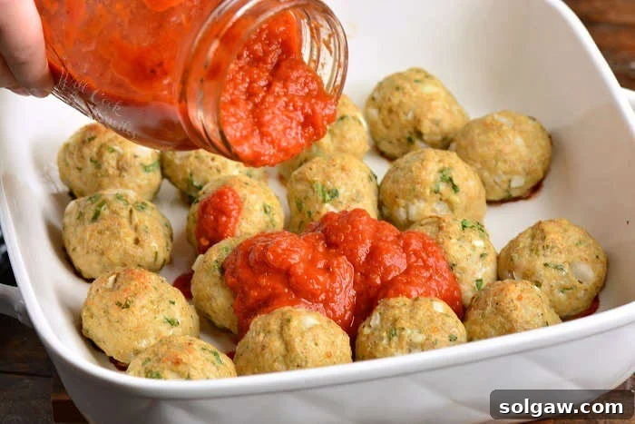 A perfectly cooked Italian chicken meatball showing a cross-section with a tender interior.