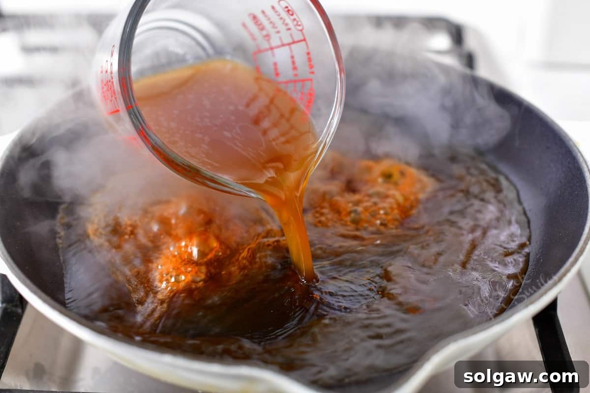 pouring beef stock into skillet to make reduction