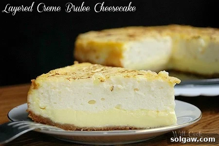 A luscious slice of Creme Brulee Cheesecake on a white plate with a fork nearby.