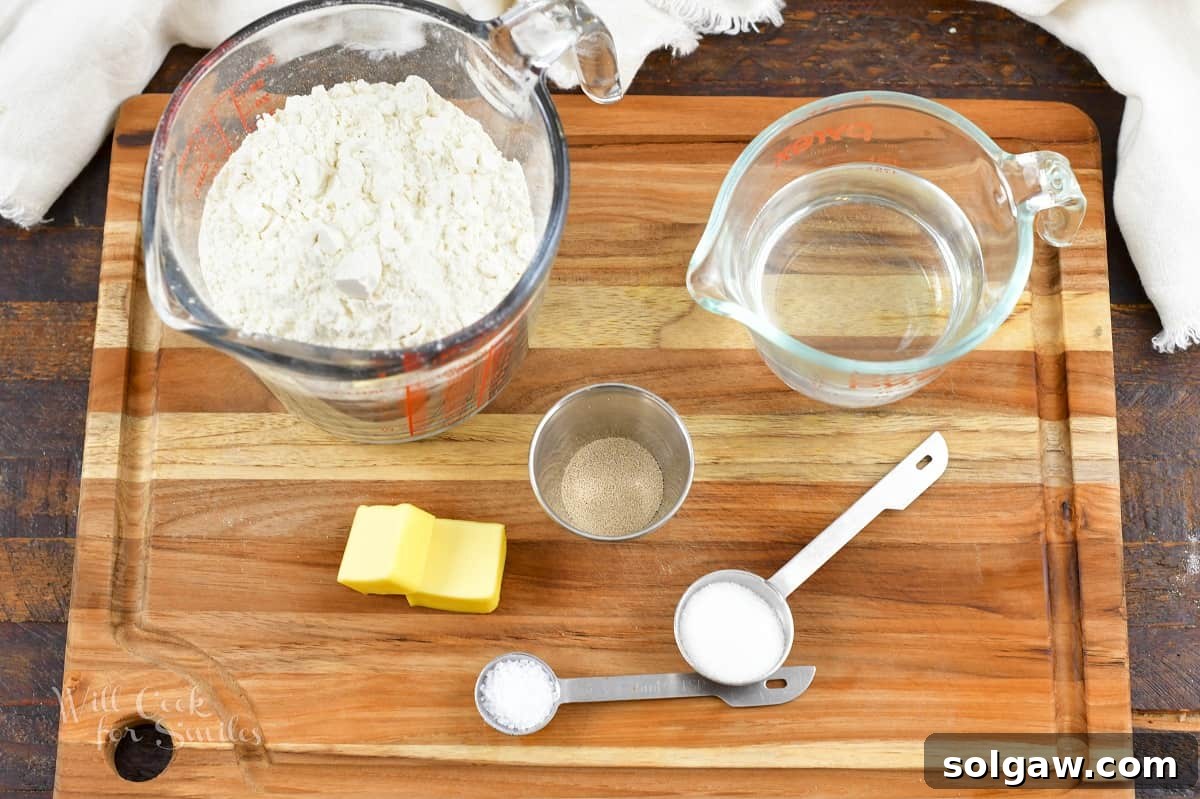 A collection of essential ingredients for making soft pretzels, including flour, yeast, sugar, salt, and butter, neatly arranged on a wooden cutting board.
