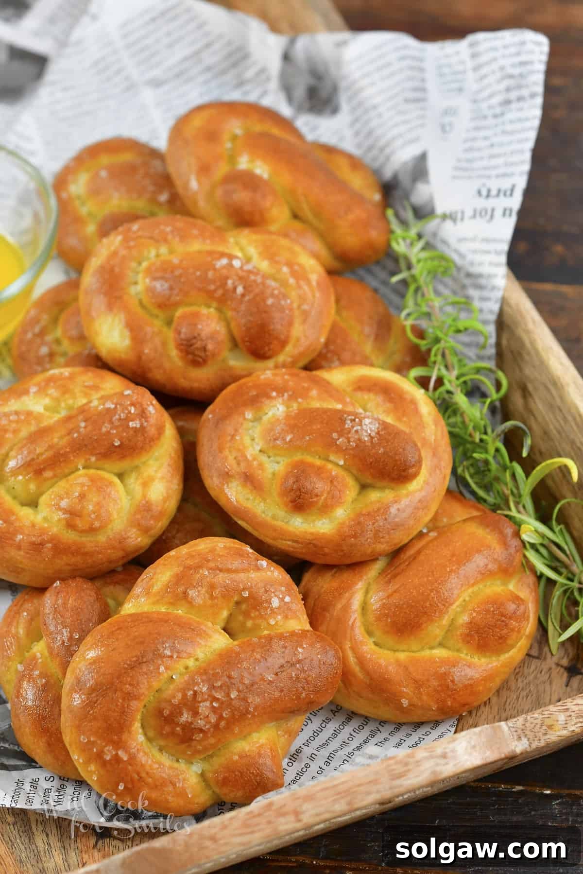 Side view of several homemade soft pretzels artfully stacked on a rustic serving tray, showcasing their golden-brown crust.