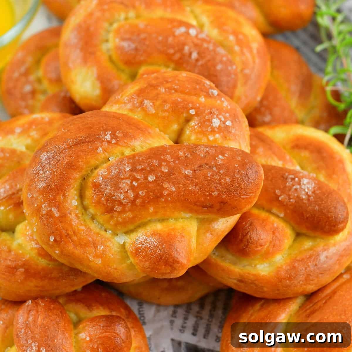 Closeup squared view of one homemade soft pretzel resting on top of several others.