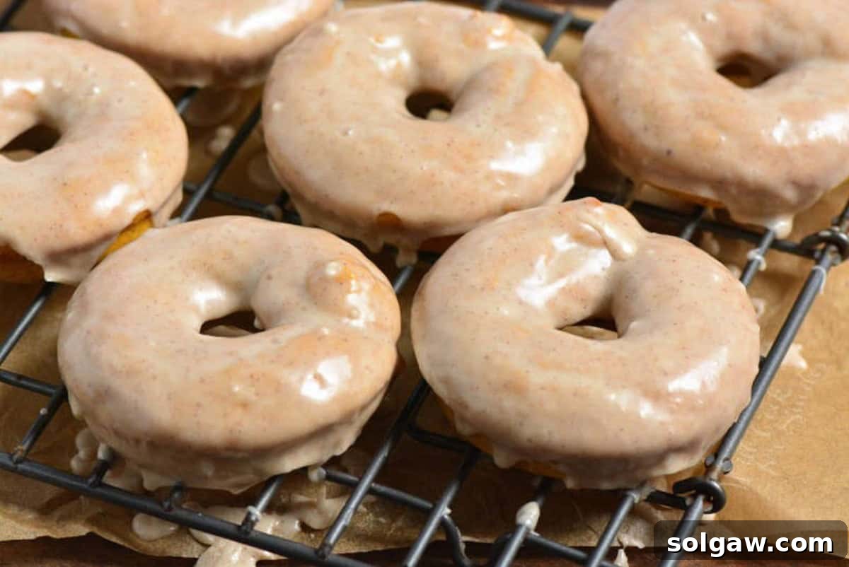 Perfectly glazed pumpkin donuts resting on a wire rack, allowing the sweet coating to set, showcasing their inviting appearance.