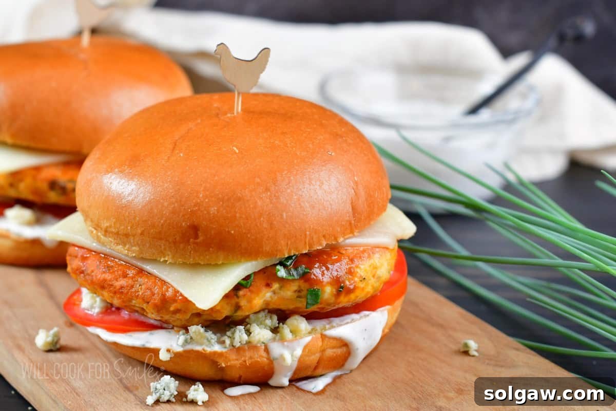 Zesty Buffalo Chicken Burger 6 Two buffalo chicken burgers neatly arranged on a cutting board, one slightly in front of the other.