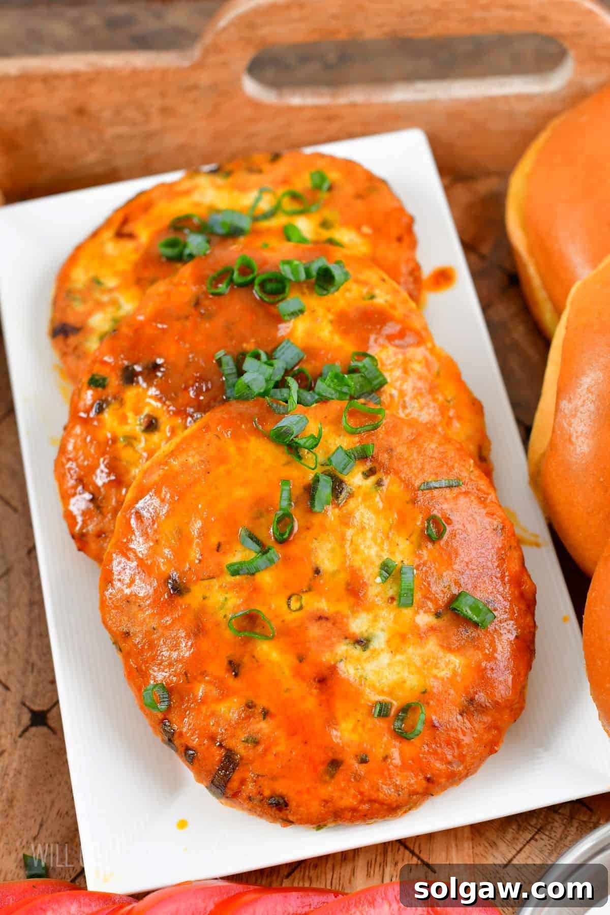 Zesty Buffalo Chicken Burger 7 Several cooked buffalo chicken patties garnished with freshly chopped green onions, ready for serving.