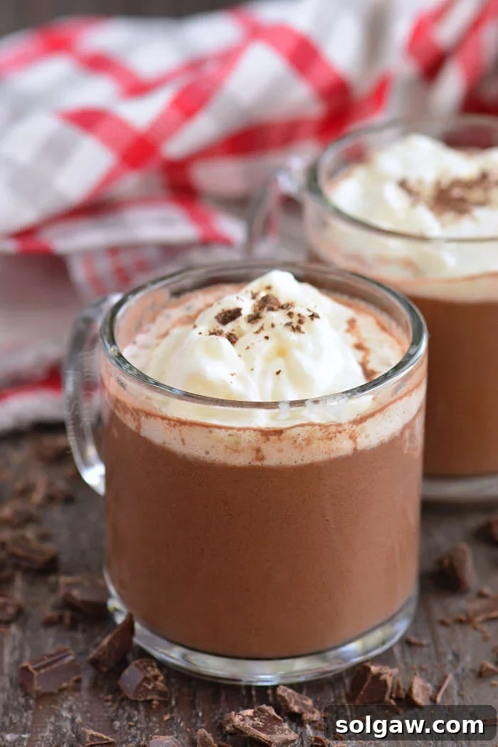 hot chocolate vertical close-up in a glass mug on a wood cutting board with chocolate shavings