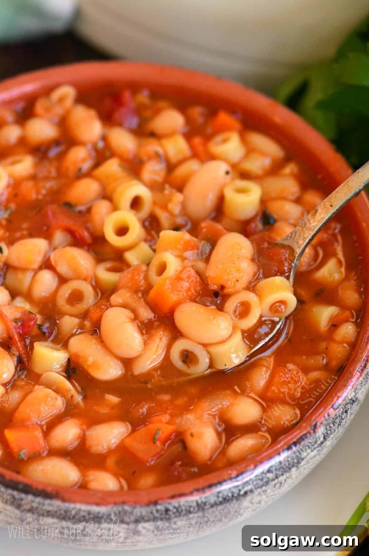 spooning out some pasta e fagioli soup from the bowl.