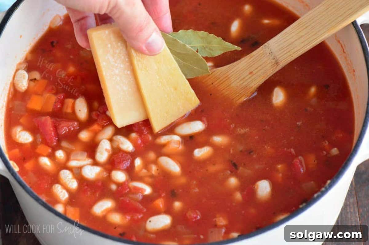 adding two parmesan rind pieces and some bay leaves to the soup.