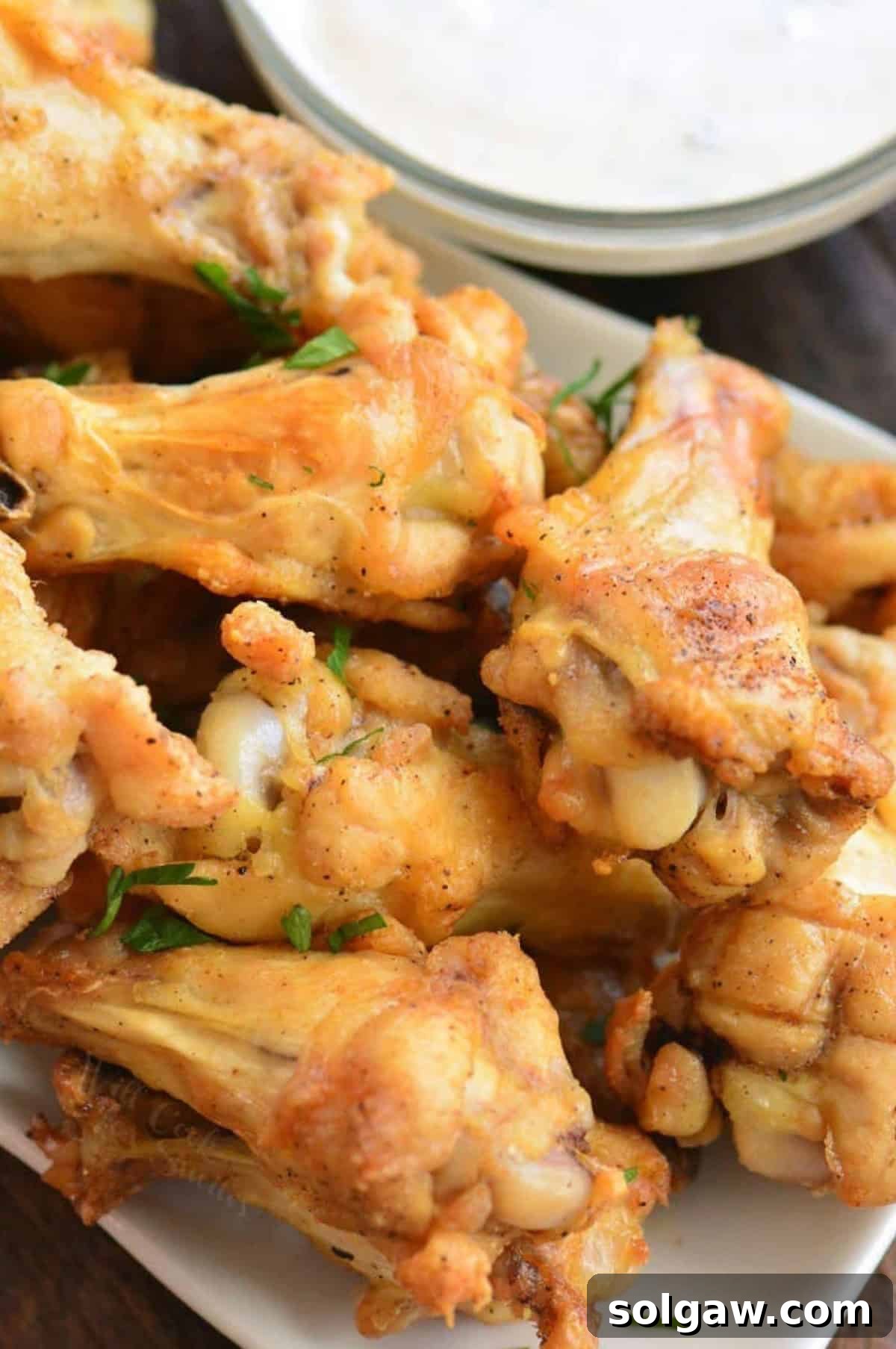 Baked chicken wings on a plate stacked up.