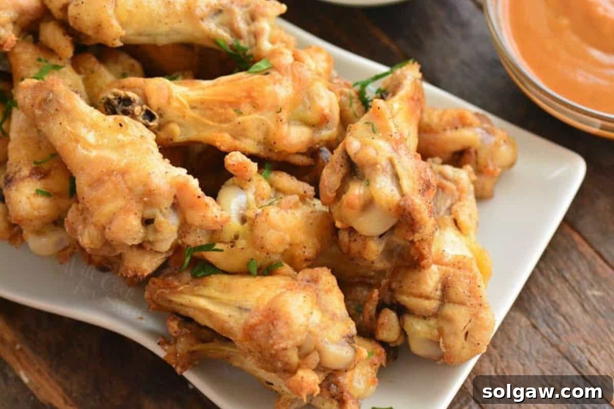Baked chicken wings on a plate on a wood surface.