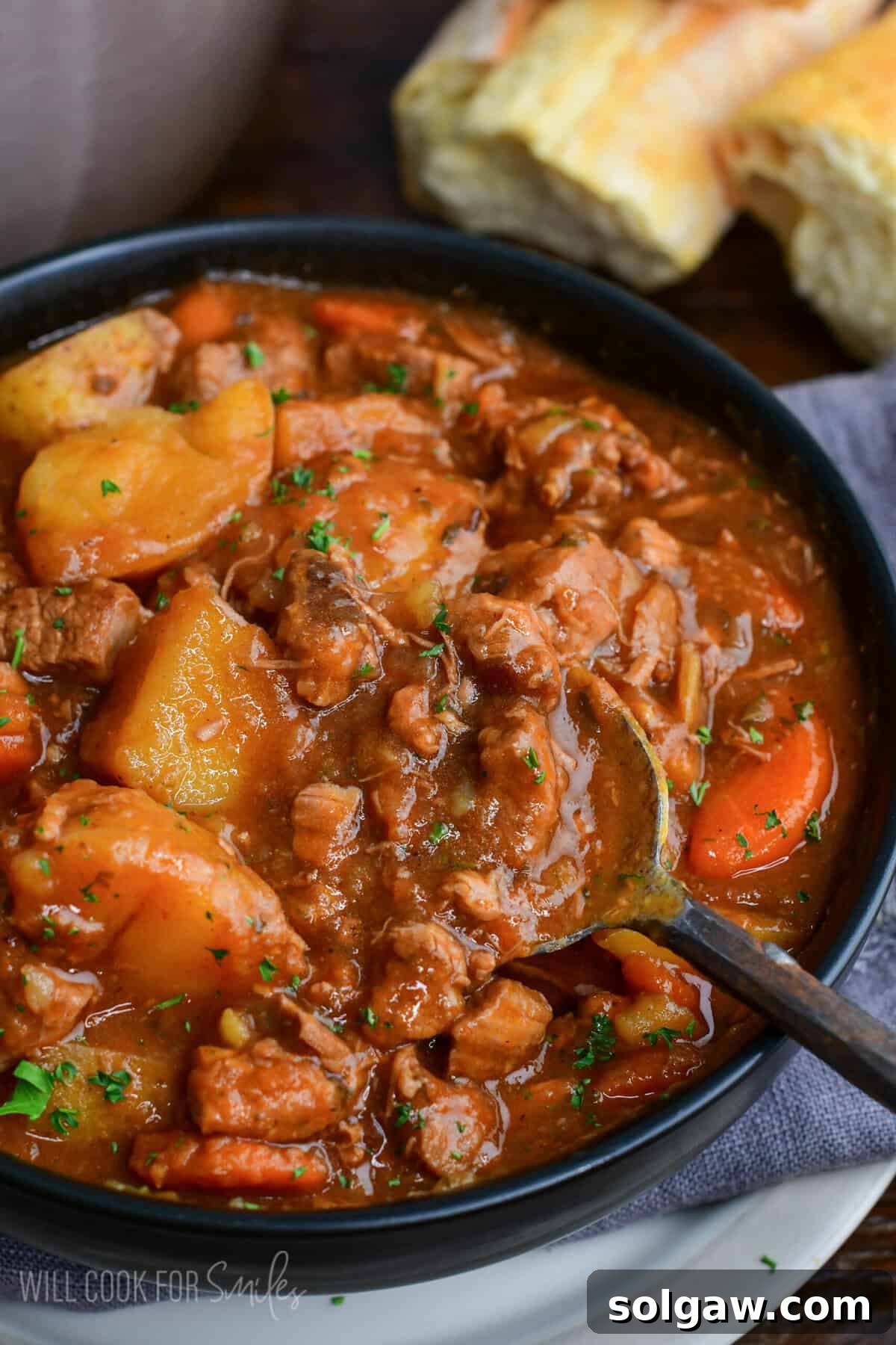 Close-up of Irish lamb stew with tender lamb, potatoes, and carrots in a rich savory broth with a spoon scooping the stew.