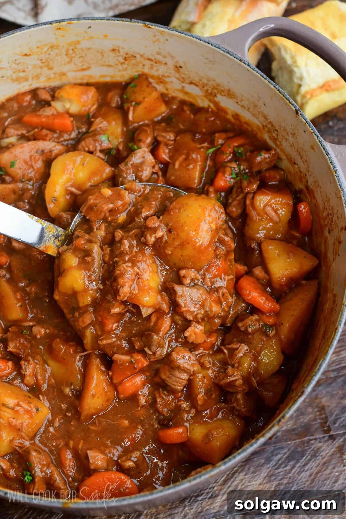 Pot of traditional Irish lamb stew with tender lamb, potatoes, and carrots in a thick savory broth with a ladle scooping the stew.