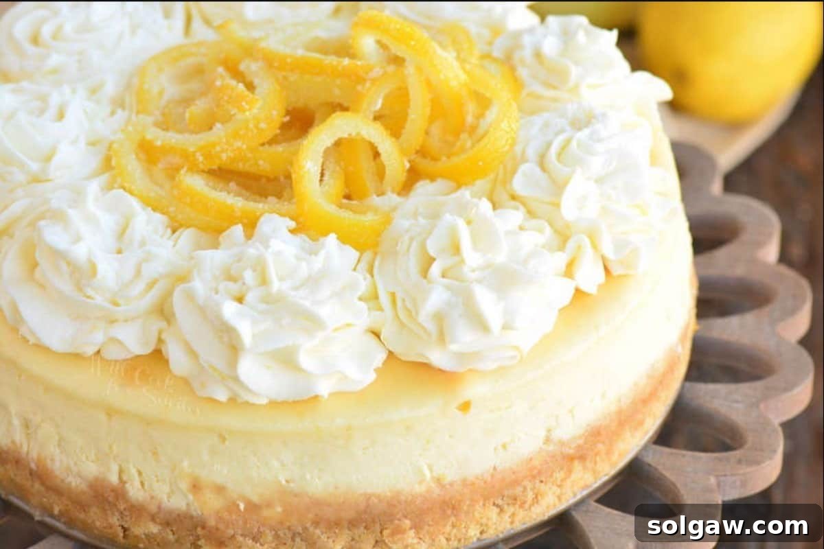 A beautifully presented whole lemon cheesecake on a cake stand, garnished with candied lemon slices and swirls of frosting.