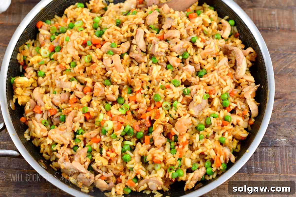 chicken fried rice in a large cooking pan on wooden board.