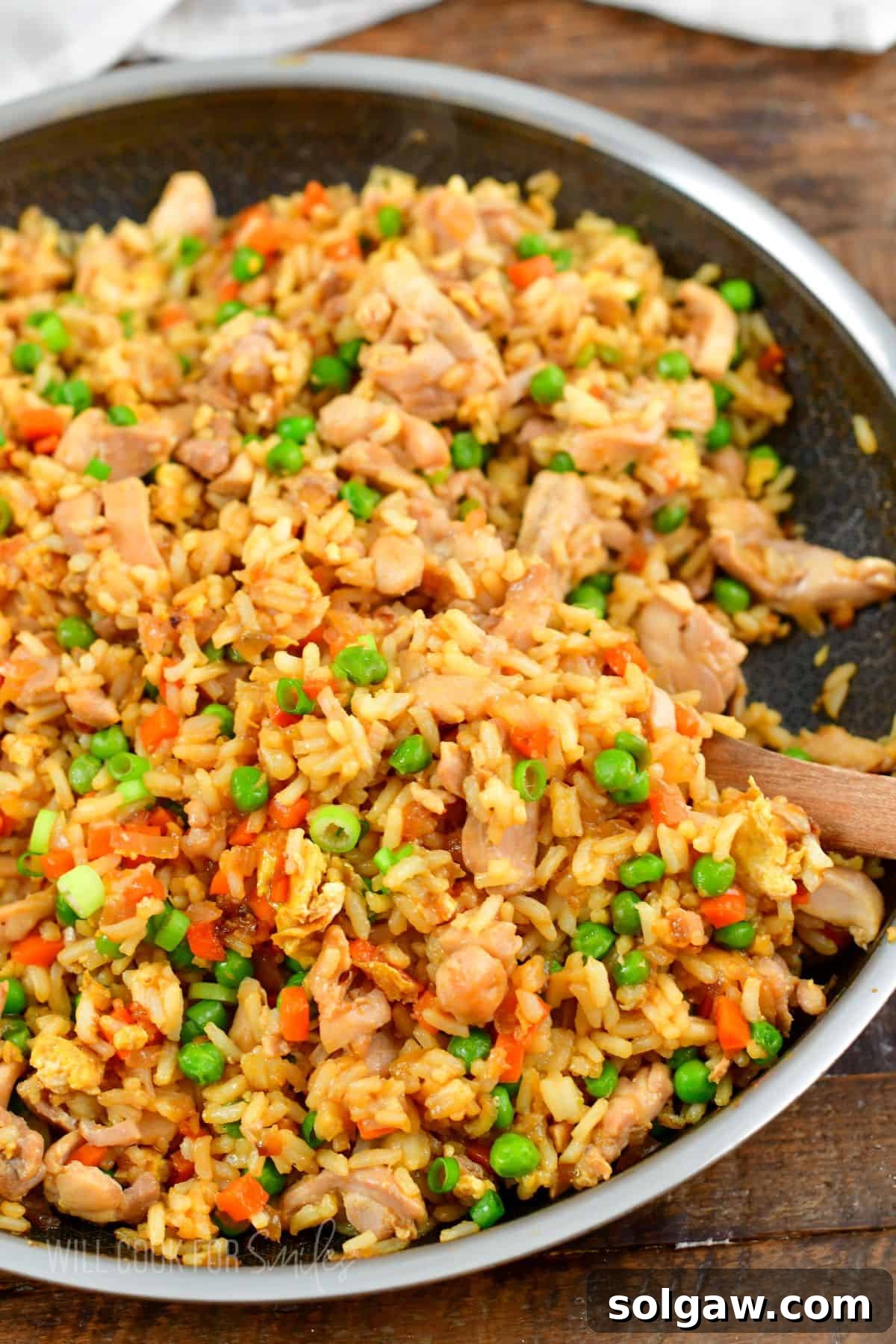 starting to scoop out some chicken fried rice from a pan with wooden spoon.