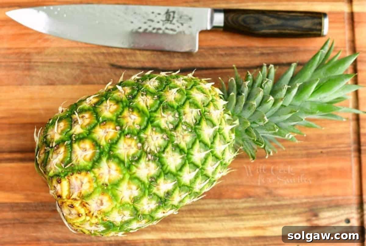 A whole, ripe pineapple resting on a rustic wooden cutting board, with a sharp chef's knife beside it, symbolizing readiness for preparation.