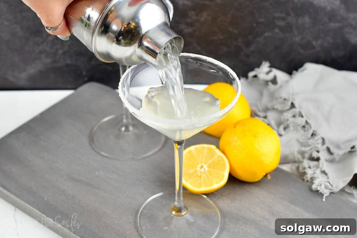 Pouring lemon drop martini into sugar rimmed glass out of the shaker.