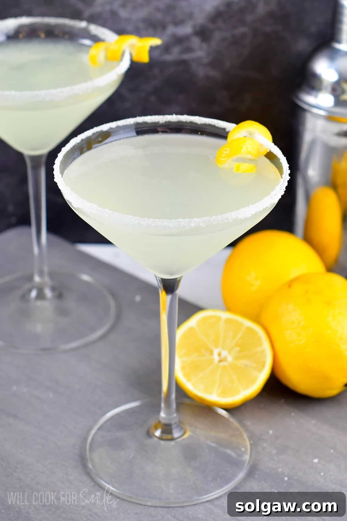 Lemon drop martini in a martini glass with sugar on the rim and a lemon twist on the side of the glass as garnish.