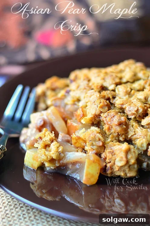 A perfectly baked Asian Pear Maple Crisp on a brown plate with a fork, ready to be enjoyed.