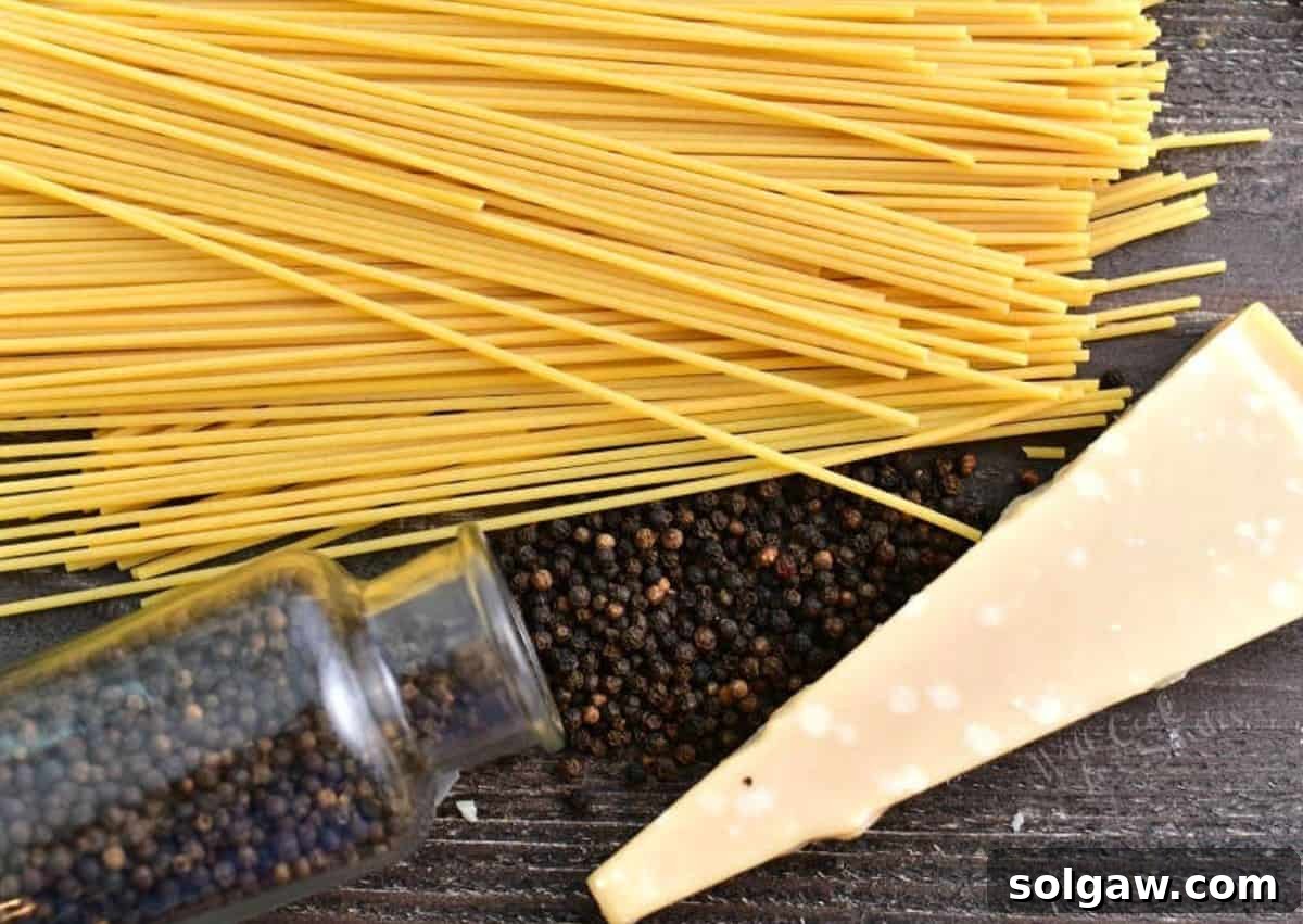 The Creamy Pepper Parmesan Pasta 3 Three essential ingredients - pasta, cheese, and peppercorns - neatly arranged on a wooden board, ready to make cacio e pepe pasta.