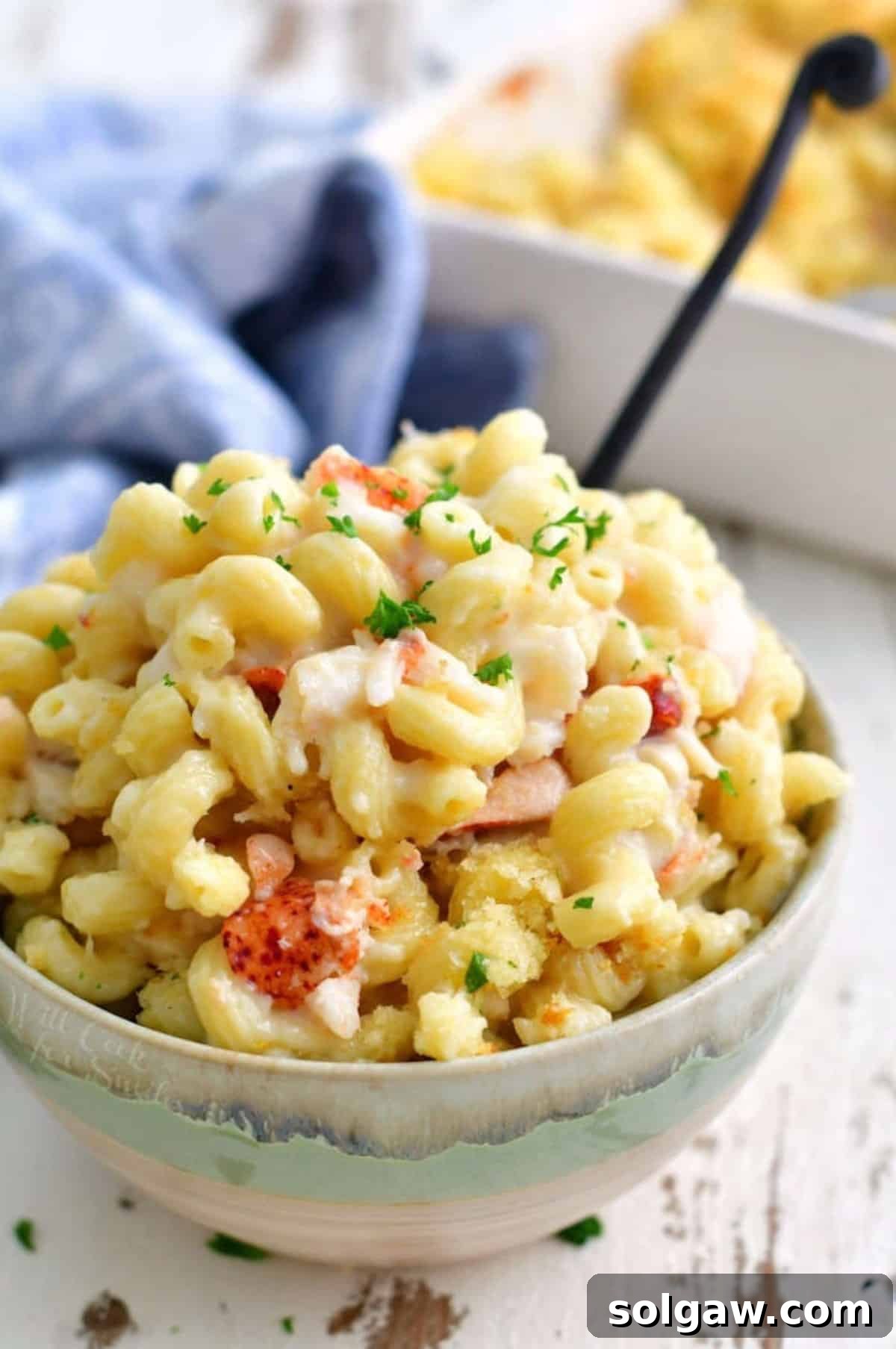 Gourmet Lobster Mac 8 A beautiful bowl full of corkscrew lobster mac and cheese with a fork, ready to be enjoyed.